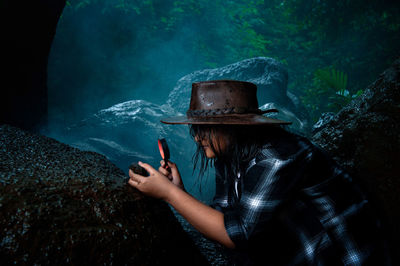 Girl examining rocks using a magnifying glass in tropical forest after rain
