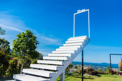 Low angle view of steps by building against blue sky
