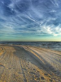 View of calm beach against cloudy sky