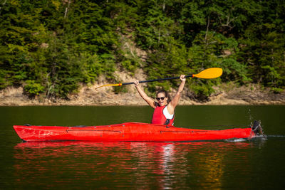 Man holding umbrella by river against trees