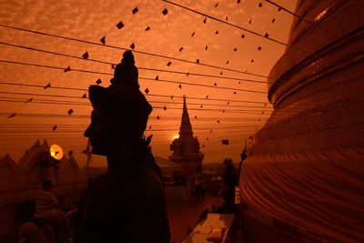 Buddha statue at temple against sky during sunset