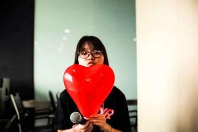 Portrait of a smiling young woman holding heart shape