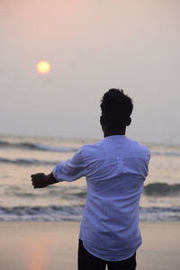 Low section of woman standing against sky during sunset