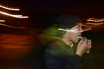 Close-up of young man eating food at night