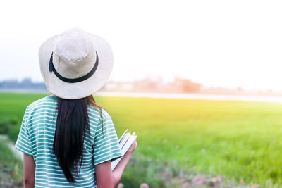 Midsection of woman wearing hat standing on field