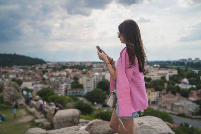 Midsection of woman using smart phone against sky