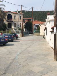 Road by buildings in city against sky