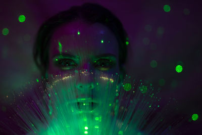 Portrait of beautiful young woman against illuminated background