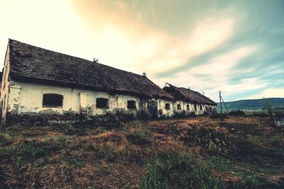 Houses on field against cloudy sky