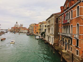 Boats in canal amidst buildings in city