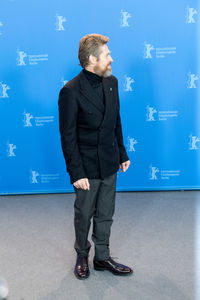 Full length of man standing against blue wall