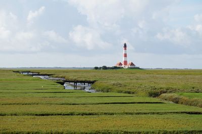 Lighthouse on field against sky