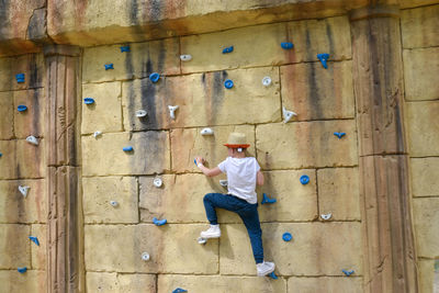 The boy is engaged in rock climbing.