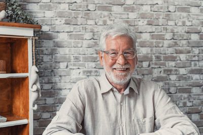 Portrait of senior man standing against wall