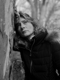 Woman looking away while leaning on wall