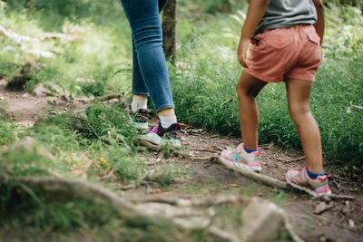 Low section of mother and daughter walking in forest