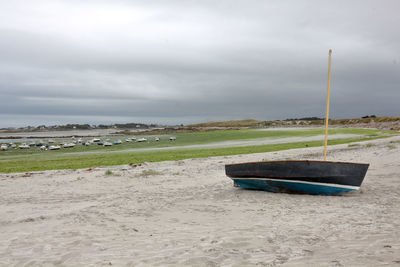 Boat moored on beach against sky