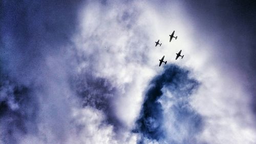 Low angle view of bird flying against cloudy sky