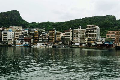 Buildings by river against sky in city