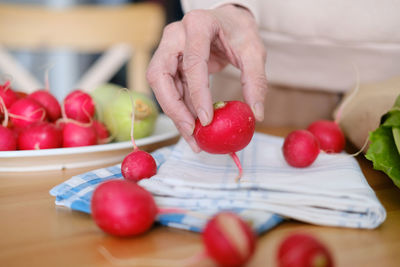 Midsection of woman holding tomatoes on table