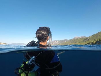 Scuba diver in sea against clear blue sky