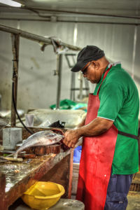 Side view of man cutting fish at market