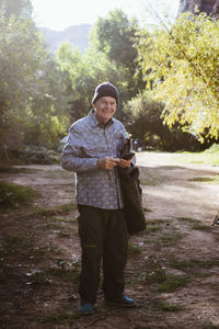 Portrait of smiling man standing on field in forest