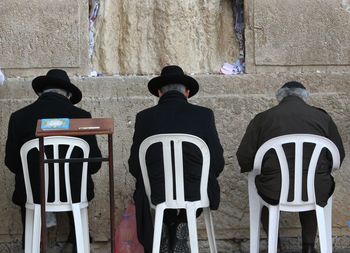 Rabbis sitting on chair in of front wailing wall