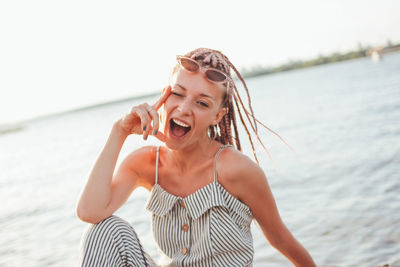 Portrait of happy young woman against lake