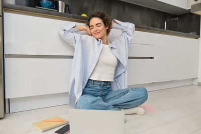 Portrait of young woman sitting on floor at home