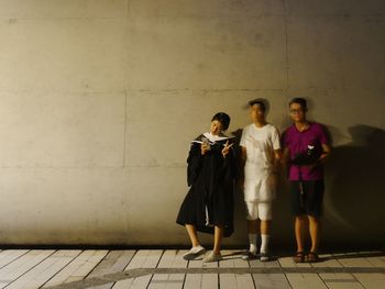 Friends standing against wall