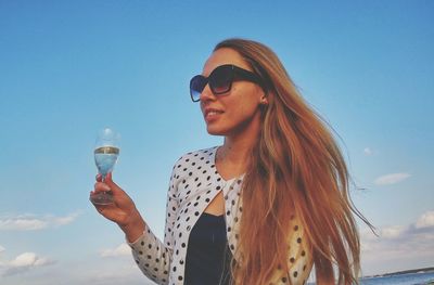 Beautiful woman holding wineglass at beach