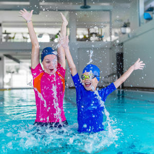 Cheerful young woman splashing water in swimming pool