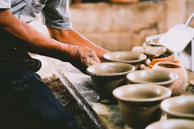 Midsection of man making pottery on table in workshop