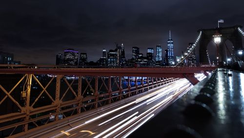Illuminated bridge in city against sky at night