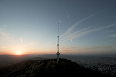 Silhouette tower and mountains against sky during sunset