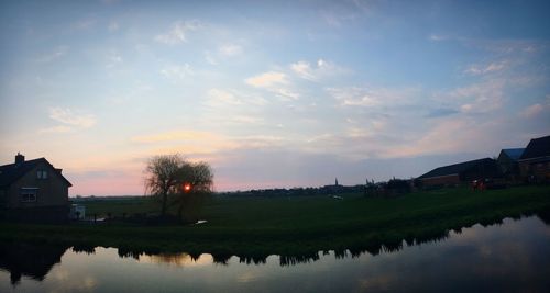 Scenic view of lake by buildings against sky during sunset