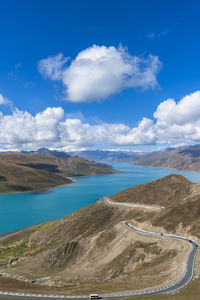 Scenic view of road by sea against blue sky