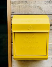 Close-up of yellow mailbox on wall