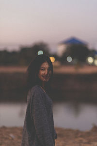 Portrait of smiling young woman standing against sky