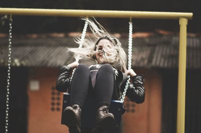 Young woman enjoying swing against building