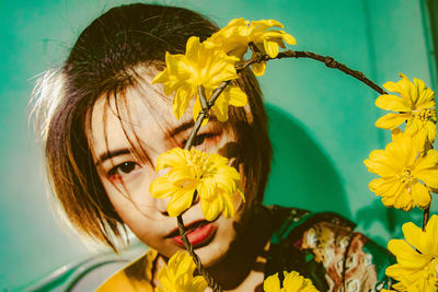 Portrait of woman by yellow flowers sitting at home