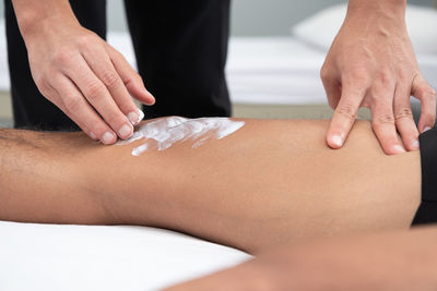 Close-up of healthcare worker applying medicine on man knee