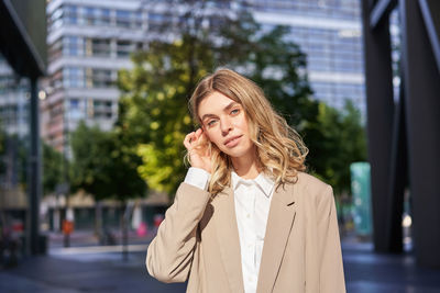 Portrait of young woman standing in city