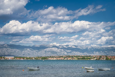 Scenic view of sea by mountains against sky