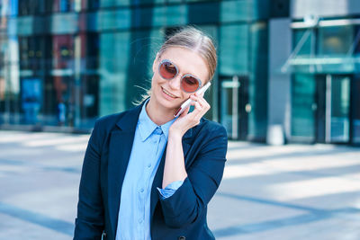 Business woman in suit uses smartphone. big city with skyscrapers