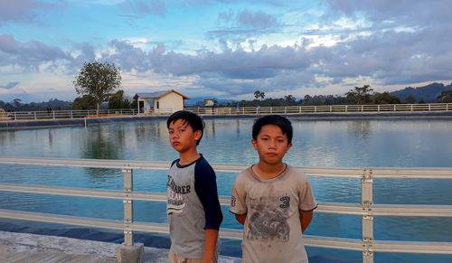 Portrait of boy standing in water against sky