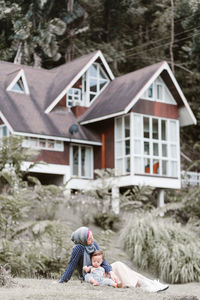 Rear view of girl outside house against trees and building