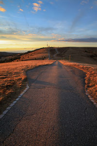 Country road against sky during sunset