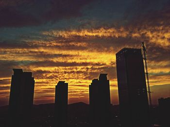 Silhouette of skyscrapers against cloudy sky